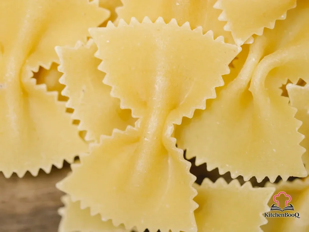 A large white serving bowl filled with bow tie pasta tossed in a creamy Parmesan Alfredo sauce and garnished with fresh chopped parsley