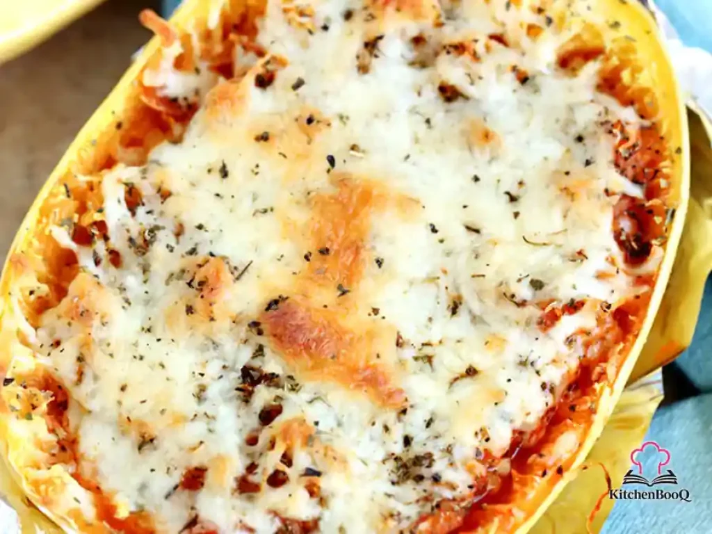 Twice-baked spaghetti squash halves filled with pasta sauce and melted bubbly mozzarella cheese, served in the squash shell on a white plate