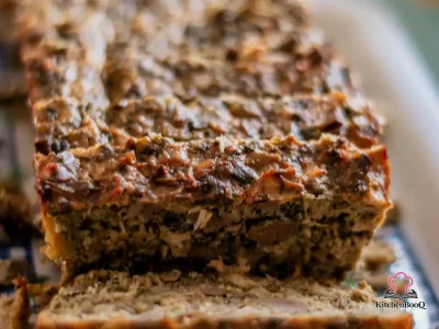 Sliced 4 ingredient stove top turkey meatloaf in a loaf pan on a wooden cutting board
