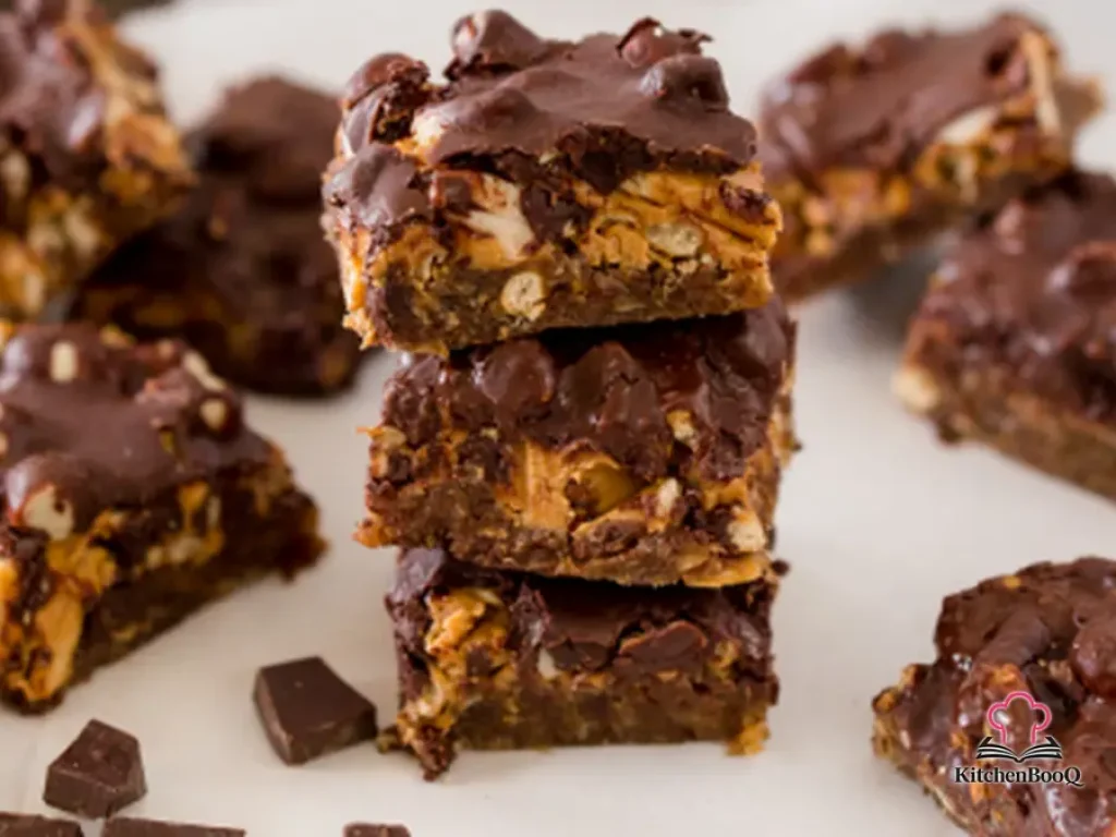 Stack of no-bake chocolate candy bars with visible pretzel chunks and a glossy dark chocolate top on parchment paper