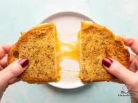 Golden crispy air fryer grilled cheese sandwich made with sourdough bread and Parmesan herb butter, sliced in half to reveal melted gooey cheese pull