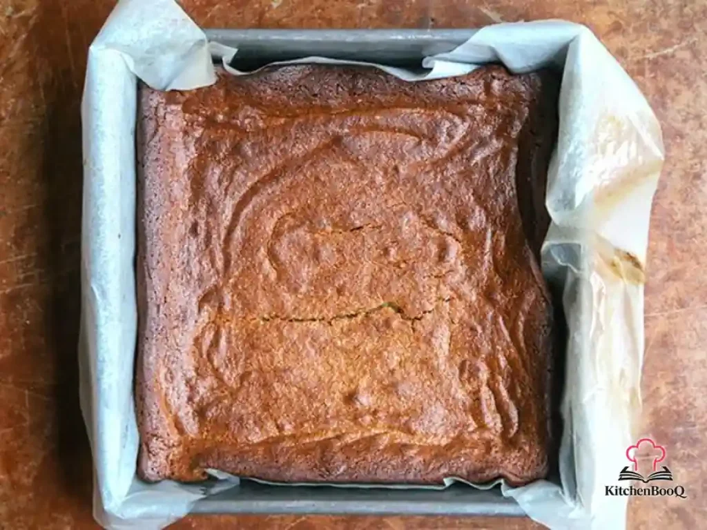 Sliced almond butter honey cake on a wooden board with a golden crumb and drizzle of honey