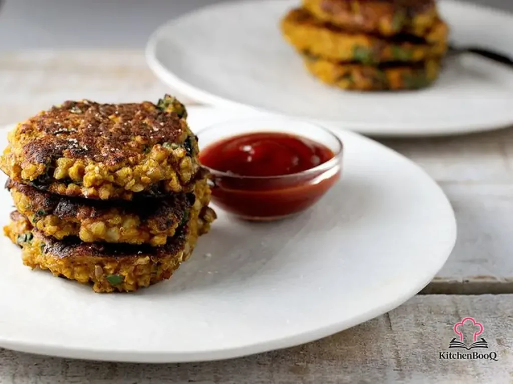 Golden crispy amaranth sweet potato and swiss chard fritters stacked on a plate with fresh herbs garnish