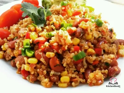 A large glass bowl of Mexican quinoa salad with pinto beans, kidney beans, corn, red bell pepper, red onion, and fresh cilantro tossed in a chili vinaigrette