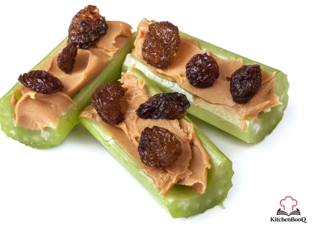 Celery stalks filled with creamy peanut butter and topped with plump raisins arranged on a white plate