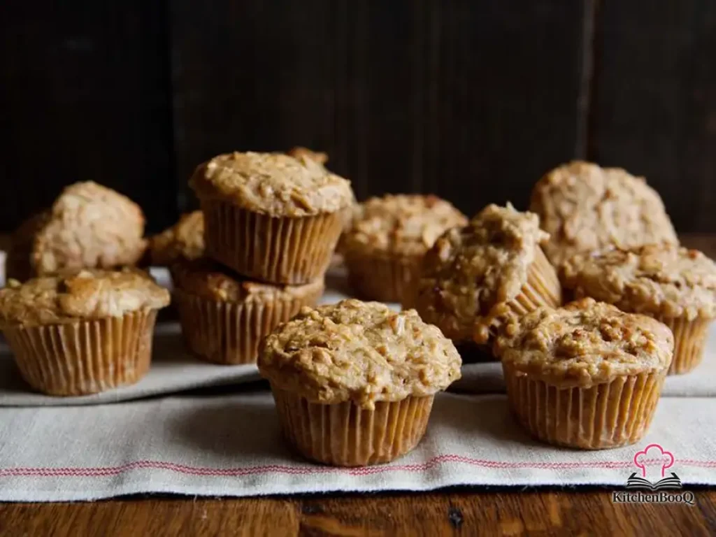 Golden apple cheddar muffins on a wire rack with visible cheese and apple, shot from above on a rustic wooden surface