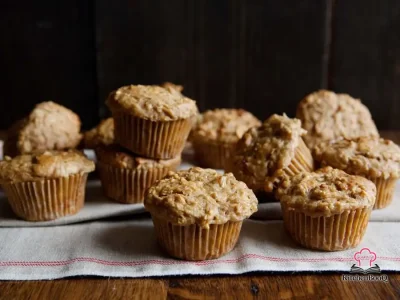 Golden apple cheddar muffins on a wire rack with visible cheese and apple, shot from above on a rustic wooden surface