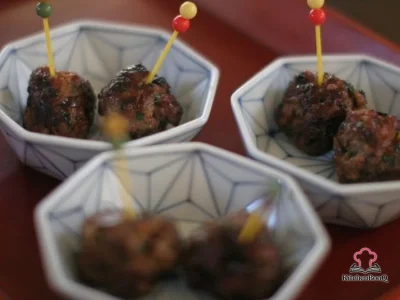 Glazed Asian-style Swedish meatballs garnished with fresh cilantro and sesame seeds on a white serving plate