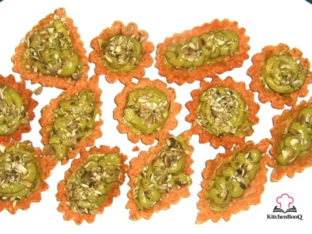 Close-up of avocado cream tartlets in walnut oat shells topped with chopped pepitas on a white serving platter