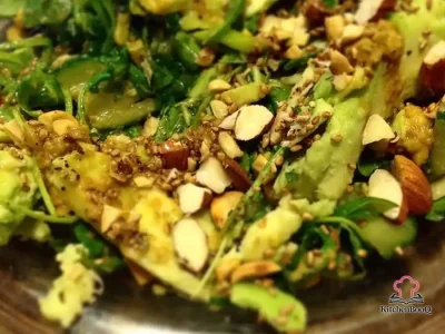 Avocado-soy dressed cucumber and rocket salad topped with toasted sesame seeds, peanuts, and almonds on a serving plate
