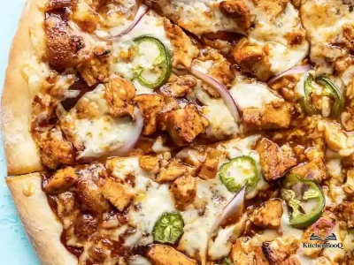 Sliced BBQ chicken pizza with Monterey jack cheese, jalapeño slices, and red onion on a golden crust, served on a wooden pizza board
