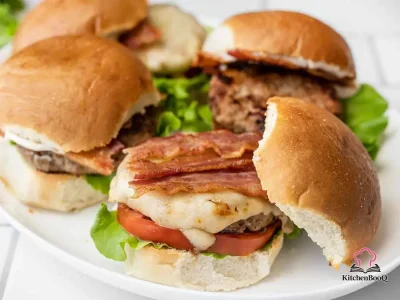 A juicy bacon ranch turkey burger stacked with crispy bacon, fresh lettuce, tomato slices, and mayonnaise on a toasted hamburger bun, served on a wooden board