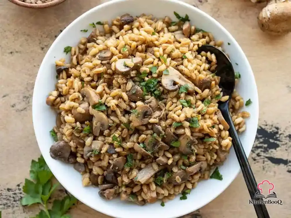 A Dutch oven filled with golden baked pearl barley and sautéed mushrooms, garnished with fresh chopped parsley