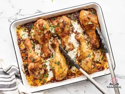 Six golden-brown baked chicken drumsticks on a baking sheet, coated in smoky paprika spice rub with crispy skin