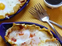 Baked eggs in a rich chipotle tomato sauce topped with melted Monterrey Jack cheese and fresh cilantro in an individual serving dish