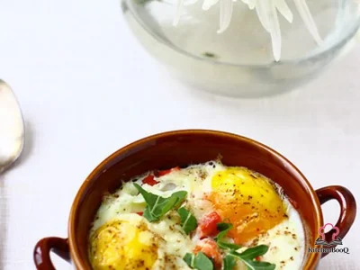 Individual ramekin of baked eggs with smoked salmon, wilted arugula, leeks, and melted Manchego cheese, garnished with fresh arugula leaves