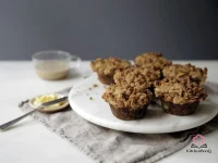Close-up of banana muffins topped with golden peanut butter granola streusel cooling on a wire rack