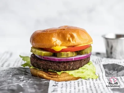 A golden-brown black bean burger patty served in a toasted bun with fresh toppings on a wooden board