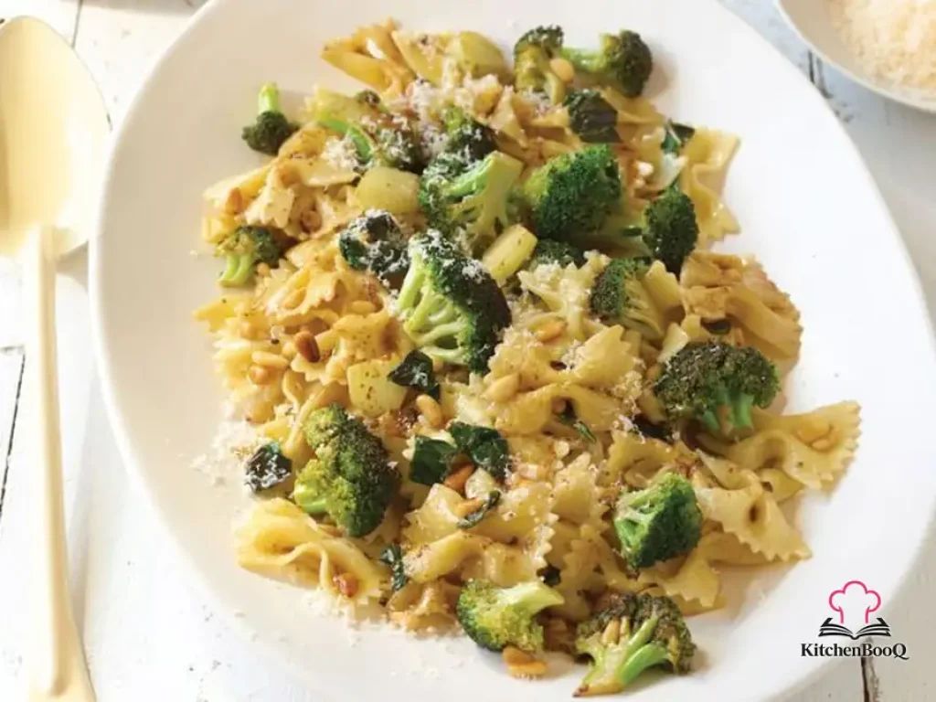 A bowl of bow-tie pasta tossed with brown butter, broccoli florets, toasted pine nuts and fresh basil, topped with shredded parmesan and a drizzle of olive oil