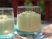 Individual glass cups filled with smooth, pale green avocado mousse garnished with lemon zest and mint leaves on a marble surface