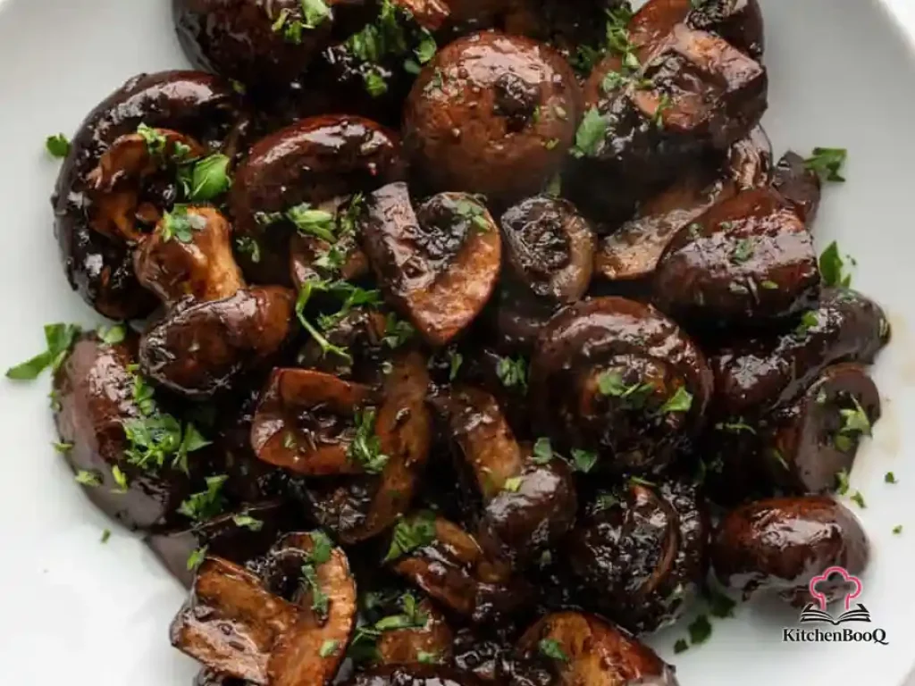 Close-up of balsamic roasted mushrooms in a ceramic baking dish, glistening with a rich balsamic glaze and garnished with fresh thyme
