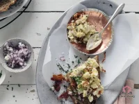 Creamy breakfast egg salad with crumbled bacon and fresh chives served on toasted whole-grain bread on a white plate