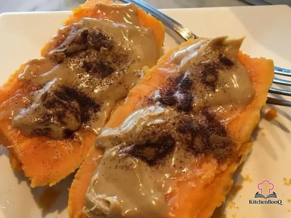 Halved breakfast sweet potato topped with peanut butter, shaved dark chocolate, and cinnamon on a rustic wooden plate