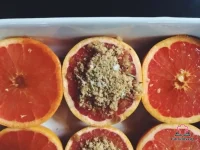 Broiled grapefruit halves caramelized with brown sugar, fresh rosemary, and flaky sea salt in a white baking dish