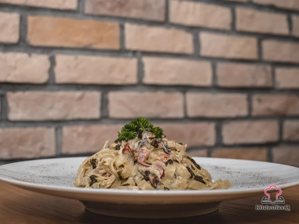 A bowl of creamy fettuccine alfredo topped with grated parmesan cheese and fresh parsley on a rustic wooden table