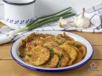 Golden crispy carrot and sage fritters on a white plate served with natural yoghurt and fried eggs