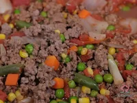 A large bowl of hearty hamburger soup with ground beef, tomatoes, and colorful mixed vegetables in a rich broth