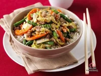 Chicken and snake bean stir-fry with carrots, wombok, and toasted sesame seeds served in a white bowl over steamed jasmine rice