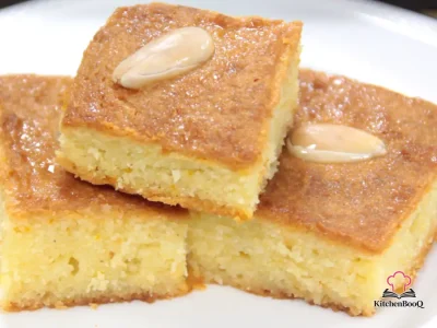 Square pieces of golden semolina basbousa cake soaked in lemon rosewater syrup with a whole almond centered on each piece