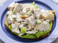 Bowl of basic chicken salad with toasted slivered almonds, chopped celery, and creamy lemon-pepper mayo dressing
