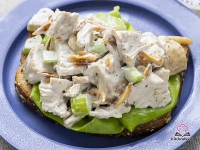 Bowl of basic chicken salad with toasted slivered almonds, chopped celery, and creamy lemon-pepper mayo dressing