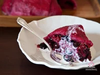 A unmolded berry summer pudding on a white serving platter, glistening with deep ruby berry juices, surrounded by fresh blueberries, raspberries, and blackberries