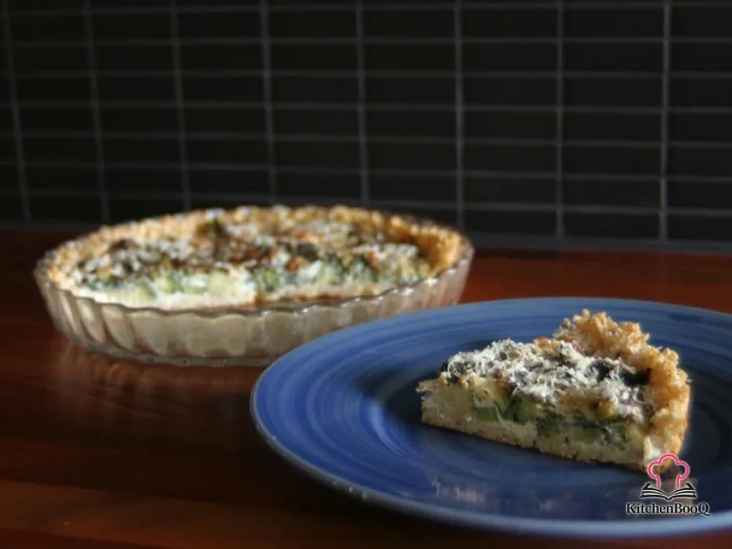 Freshly baked brown rice broccoli tart in a round tart pan with golden Parmesan topping and visible broccoli florets