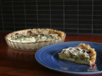 Freshly baked brown rice broccoli tart in a round tart pan with golden Parmesan topping and visible broccoli florets