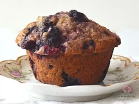 Golden buttermilk berry muffins with a crunchy Turbinado sugar topping and juicy mixed berries visible through the domed tops, arranged on a wire cooling rack