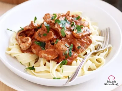 A bowl of diabetes-friendly pork stroganoff served over fettuccine with steamed green beans and fresh parsley garnish