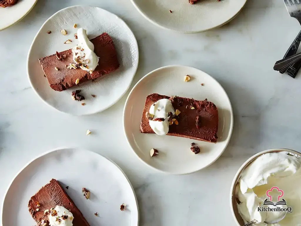 Sliced bittersweet chocolate semifreddo on a white serving platter garnished with whipped cream and chocolate shavings