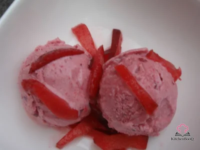 Scoops of deep ruby blood plum sherbet in a white bowl topped with fresh sugar-dusted plum slices