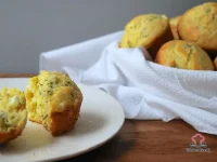 Golden cheesy herbed corn muffins with feta and fresh herbs on a wire cooling rack